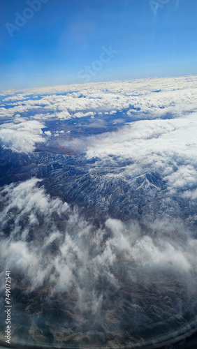 an aerial shot for majestic mountain ranges covered in snow and powerful clouds and blue sky in California USA