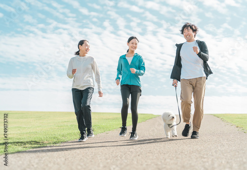 青空の見える公園で犬の散歩・運動・トレーニング・有酸素運動をするさわやかな家族・親子 
