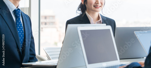 会社・企業・オフィスでノートパソコン・pcを使って仕事するスーツ姿の男女
 photo