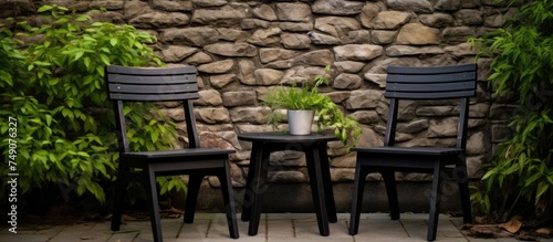 Two black chairs made of wood are positioned side by side against an outdoor wall. The chairs appear sturdy and simple in design, ready for use.