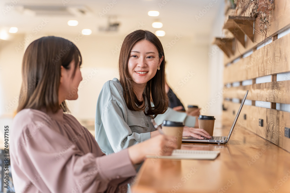 カフェのカウンターで仕事・ミーティングするビジネスウーマン（ノマドワーカー・相談・会議）
