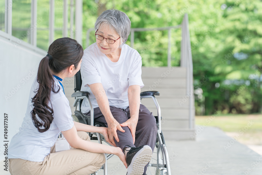 車椅子に乗る高齢者と介護士（ふくらはぎ・足首）
