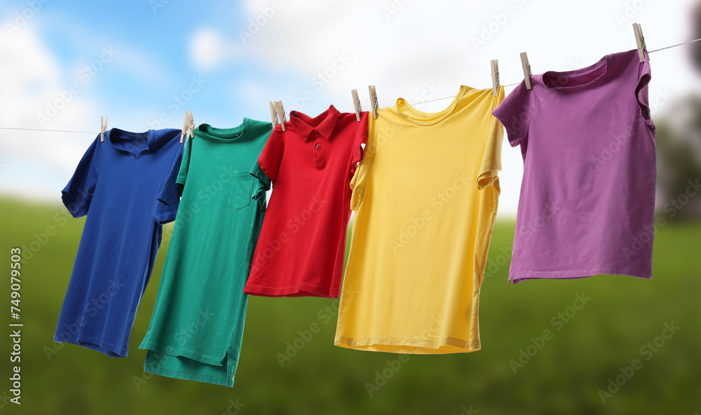 Different t-shirts drying on washing line outdoors, banner design