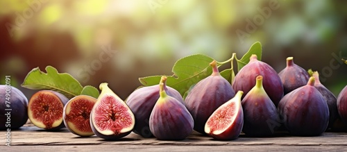 A collection of ripe fig fruits is neatly arranged on a wooden table, creating a visually appealing display. The figs sit elegantly, showcasing their natural beauty and rich colors. photo