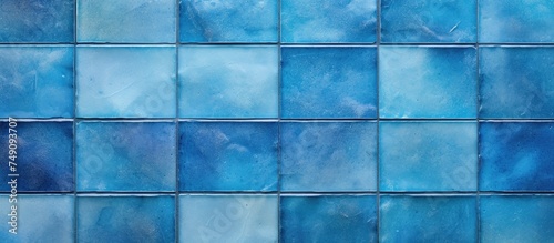 Detailed view of a blue ceramic tile wall, showcasing the texture and color variation of the tiles. Each tile is arranged in a precise pattern, creating a uniform and structured appearance.