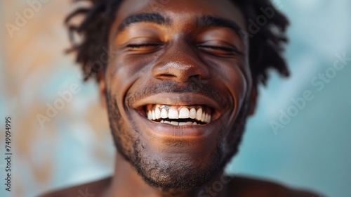 Handsome unshaven young dark-skinned male laughing out loud at funn photo