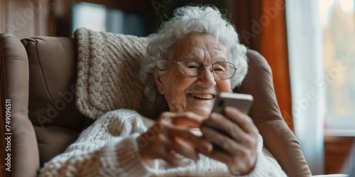 Grandma sitting at home and is happy to receive a message on the cell phone.