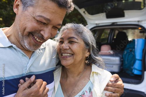 Senior biracial couple shares a joyful moment, with the man embracing the woman