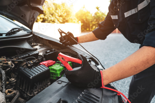 Hand car mechanic holding car booster cables for jump start car for empty battery dead and low voltage power problem or fix service maintenance accident assistance technician and energy charge. photo
