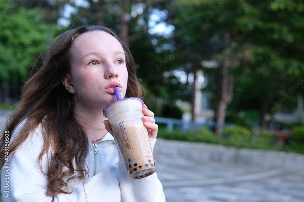 Delicious drink Bubble Tea drinking delicious coffee tea smoothie on the street a young girl happily pulls liquid from a straw chews swallows yami yami. Delicious drink Bubble Tea drinking delicious coffee tea smoothie on the street a young girl happily pulls liquid from a straw chews swallows yami yami.