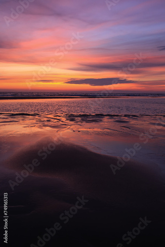 sunset sky is reflecting in the low tide draining waters of a beach in Sylt Island  Germany