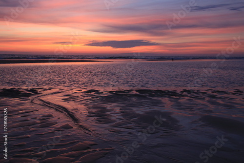 sunset sky is reflecting in the low tide draining waters of a beach in Sylt Island  Germany