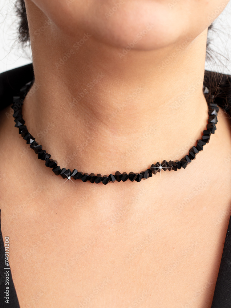 A necklace of black stones on a girl’s neck. Close-up