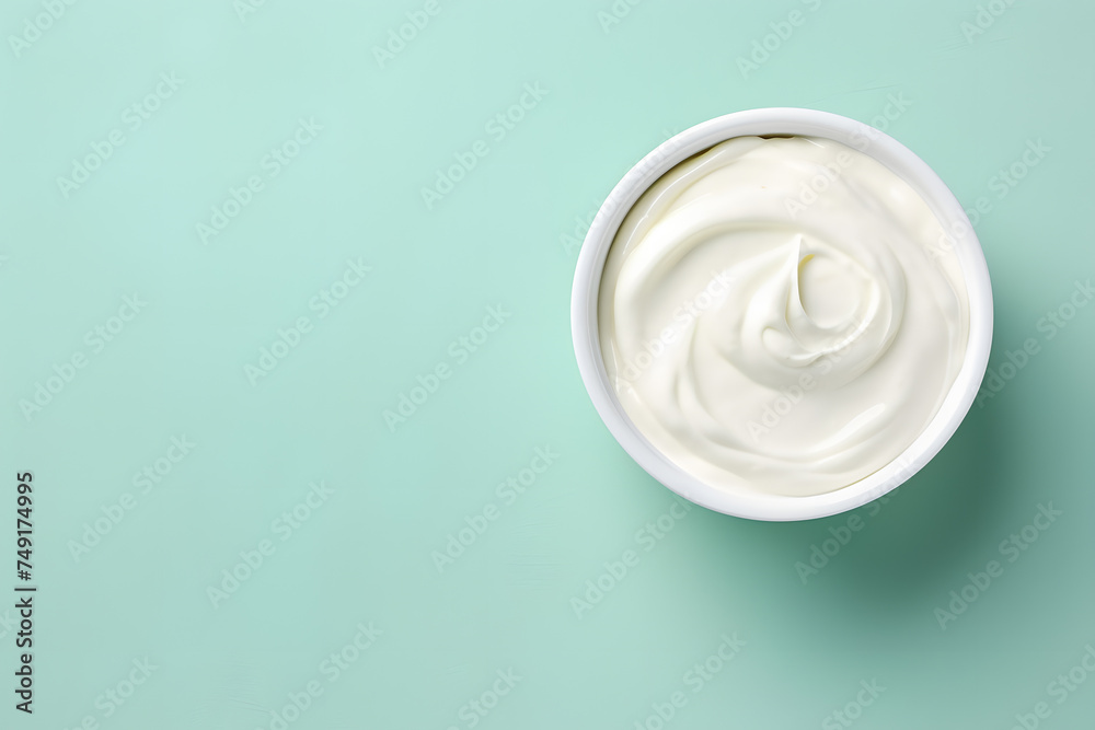 Top view of bowl with white quark or cream on side of mint green background with copy space Top view of bowl with white quark or cream on side of mint green background with copy space