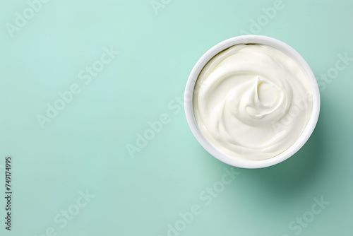 Top view of bowl with white quark or cream on side of mint green background with copy space
