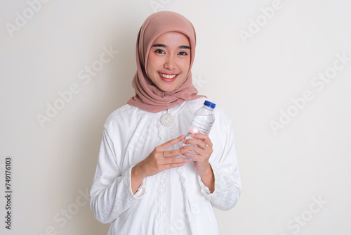 Moslem Asian woman smiling happy while holding a plastic drink bottle photo