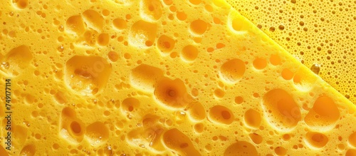 A close up view of a bright yellow sponge commonly used for washing dishes, showing its texture and color against a diverse background.