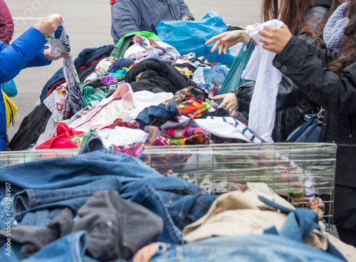 People choosing second-hand clothes at a flea market. Sustainable lifestyle, thrifting and upcycling concept.