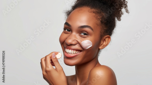 joyful woman with a dab of cosmetic cream on her cheek, indicative of skincare and beauty routines