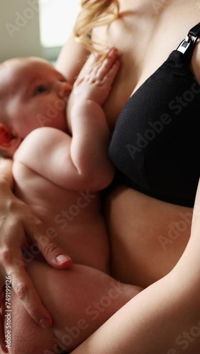 close-up of naked baby sucking mother's breast. breastfeeding. vertical video