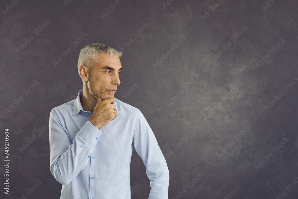 Pensive middle-aged Caucasian man on black studio background look at blank empty copy space thinking making decision. Thoughtful serious male consider or make plan. Copyspace. Dilemma concept. Pensive middle-aged Caucasian man on black studio background look at blank empty copy space thinking making decision. Thoughtful serious male consider or make plan. Copyspace. Dilemma concept.
