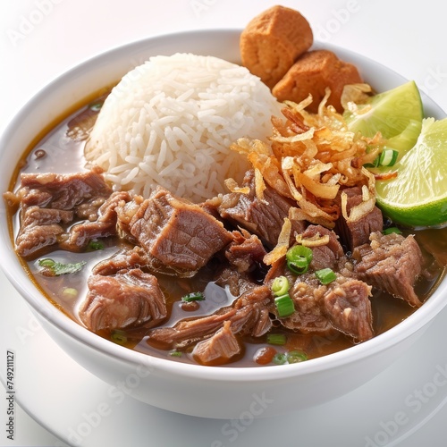 Coto Makassar: A traditional beef soup from Makassar, South Sulawesi, made with tender beef, offal, and spices, typically served with steamed rice and garnished with fried shallots and lime wedges photo