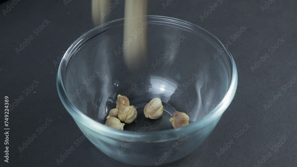 cardamom sprinkled into a glass bowl on a black table cardamom sprinkled into a glass bowl on a black table