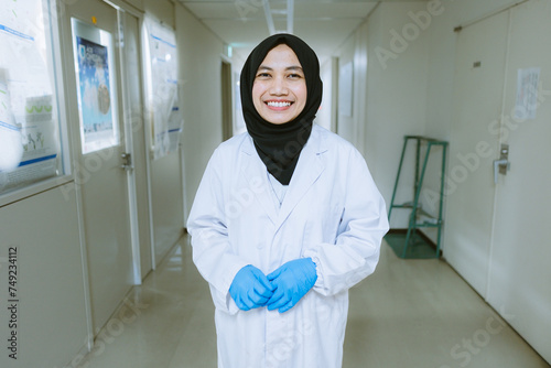 Smiling Muslim Scientist in White Lab Coat Standing in Laboratory Corridor, Facing Camera