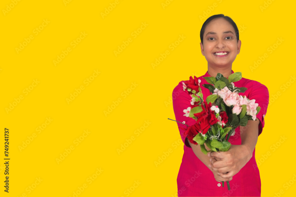 A young girl smiling and holding a red and white flowers Bouquet in both hands, A young girl wearing a pink dress, looking at the camera and copy space on the right side