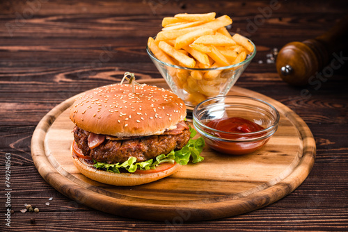 American food beef burger with bacon, tomato and lettuce with french fries and ketchup.