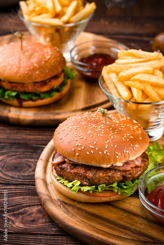 American burgers with beef, chicken, bacon, tomato and lettuce with french fries and ketchup.