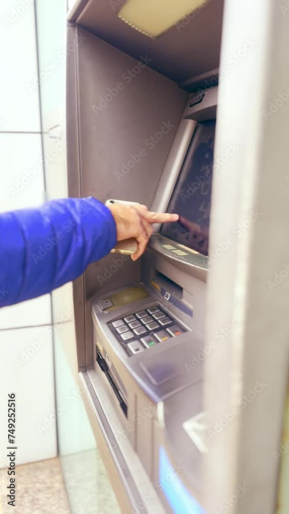 an ATM transaction, a man's hand holding a phone makes a financial transaction. This scene illustrates the convenience of modern banking by combining digital technology with money transactionsVertical an ATM transaction, a man's hand holding a phone makes a financial transaction. This scene illustrates the convenience of modern banking by combining digital technology with money transactionsVertical
