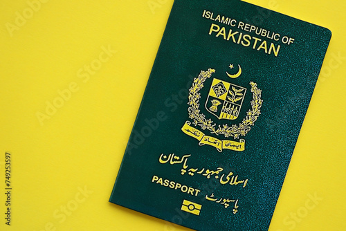 Green Islamic Republic of Pakistan passport on yellow background close up. Tourism and citizenship concept photo