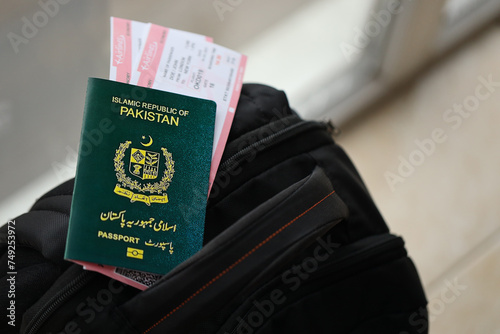 Green Islamic Republic of Pakistan passport with airline tickets on touristic backpack close up. Tourism and travel concept