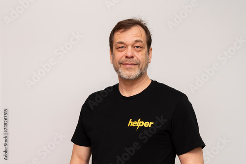 Bild auf Leinwand Elderly man 50-55 years old wearing a black T-shirt that says: Helper