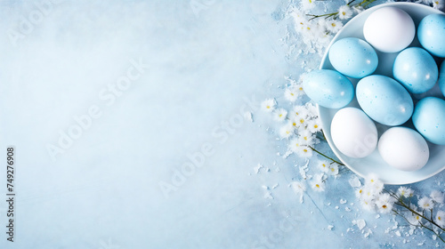 A bowl with colored eggs and some fresh spring flowers on light blue background with copy-space. Easter themed and Created with AI.
