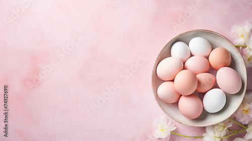 A bowl with colored eggs and some fresh spring flowers on light pink background with copy-space. Easter themed and Created with AI.