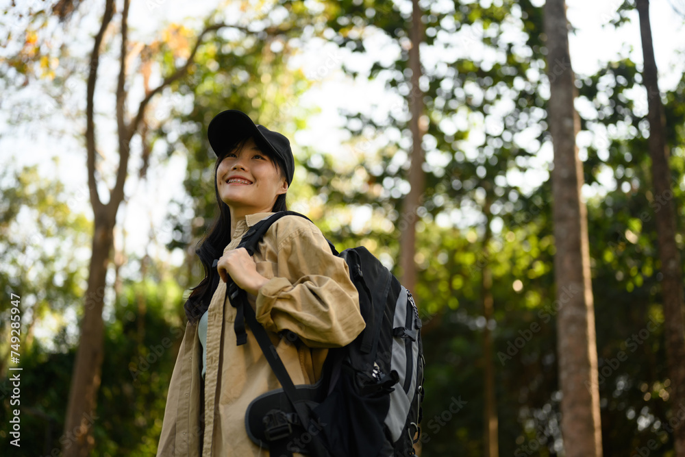Relaxed young woman with backpack trekking in forest and enjoying nature Relaxed young woman with backpack trekking in forest and enjoying nature