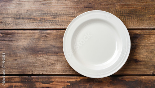 Empty plate on rustic wooden background. Top view; space for text; stock photo