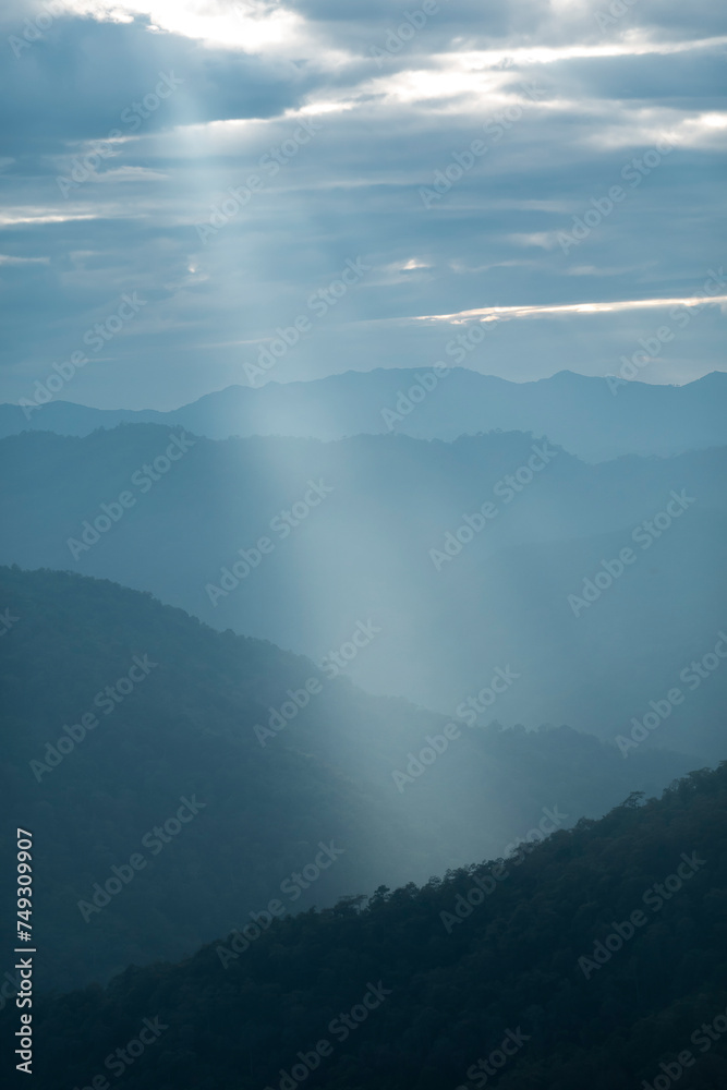 Sun rays filter through the clouds in hills of the valley illuminated by the sun's rays filtering through the clouds