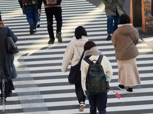 冬の朝の街の交差点の横断歩道を渡る人々の姿