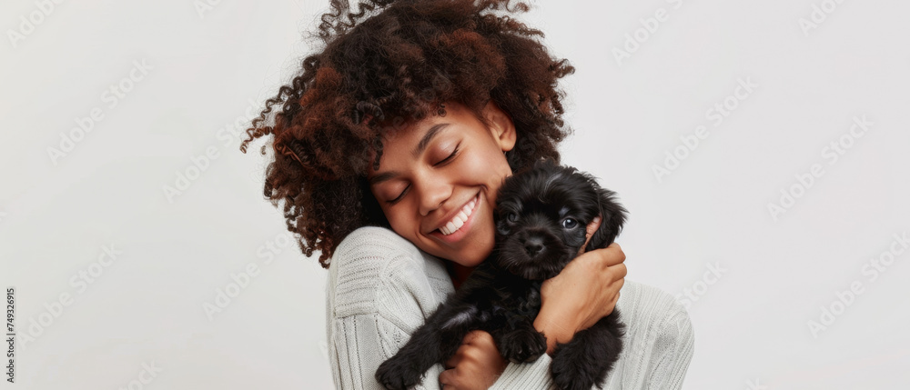 Joyful young woman embraces a tiny puppy with a tender, loving bond shining in her eyes. Joyful young woman embraces a tiny puppy with a tender, loving bond shining in her eyes.