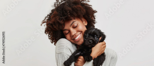 Joyful young woman embraces a tiny puppy with a tender, loving bond shining in her eyes.