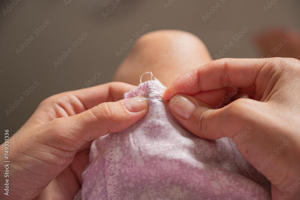seamstress hands with a needle, repairing clothes using thread and needle. Clothing repair seamstress hands with a needle, repairing clothes using thread and needle. Clothing repair