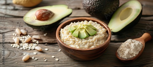 A wooden bowl filled with oatmeal sits next to a ripe avocado on a wooden table. The creamy oatmeal contrasts with the smooth texture of the avocado, creating a wholesome and nutritious breakfast or