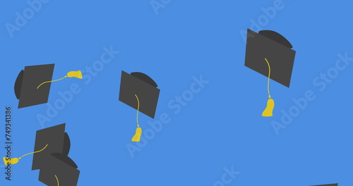 Digital image of multiple graduation hat icons falling against blue background