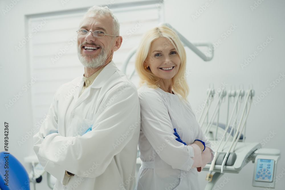 Male and female dental doctors wearing face sitting at his clinic. Male and female dental doctors wearing face sitting at his clinic.
