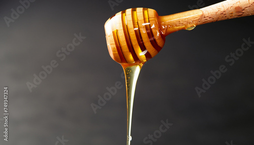 honey dripping from dipper or spoon on black background, closeup shot with copy space