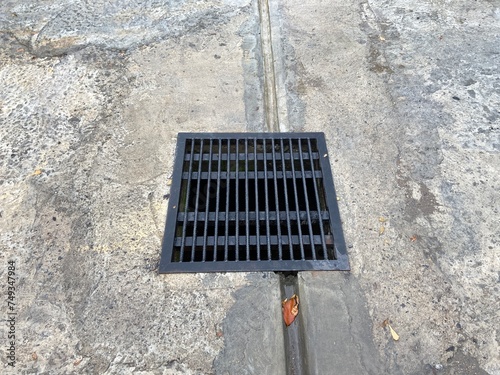 a square black iron grille for underground water channels in the parking area