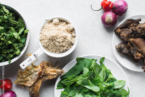mise en place of ingredients of egusi soup, process of making egusi vegetable soup, top view of water leaf, ugwu, egusi and pepper on a table photo
